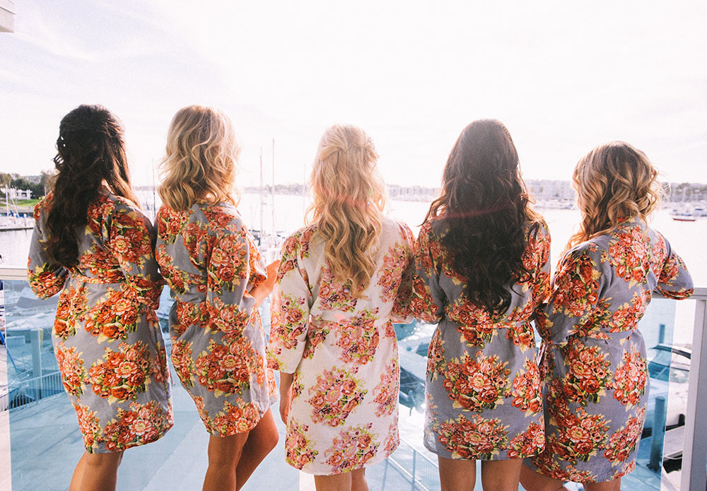bride and bridesmaids in robes looking out at the marina