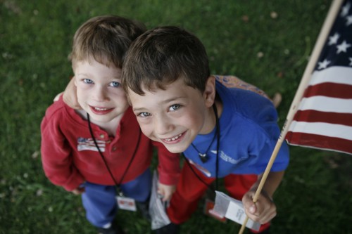 2 young boys smiling holding the American flag