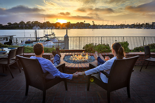 couple sitting in front of fire pit looking at sunset on the marina