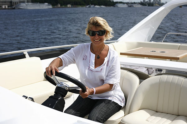 adult woman behind a steering wheel of a yacht