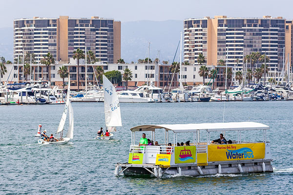 people riding waterbus with sailboats close by