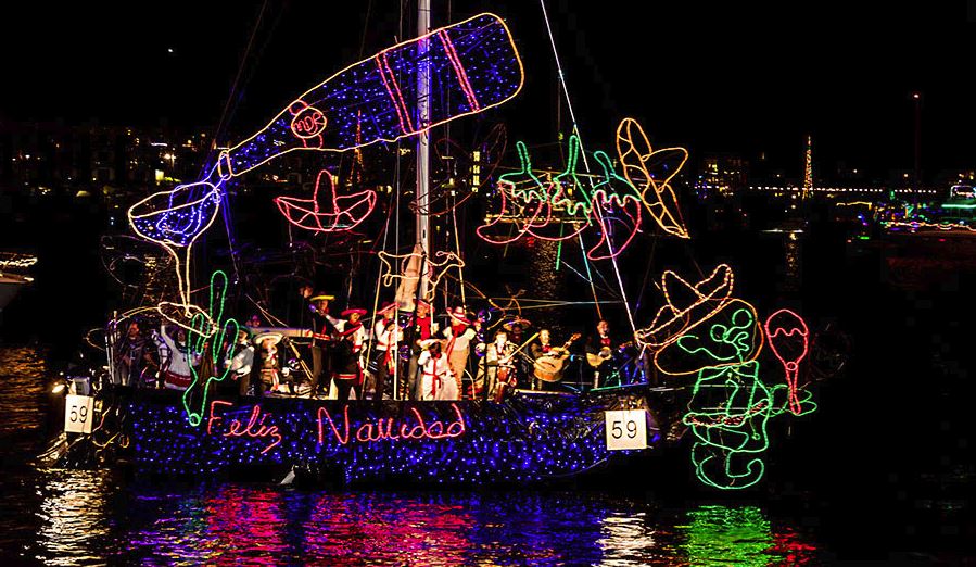 boat decorated with lights spelling out Feliz Navidad and mariachi band