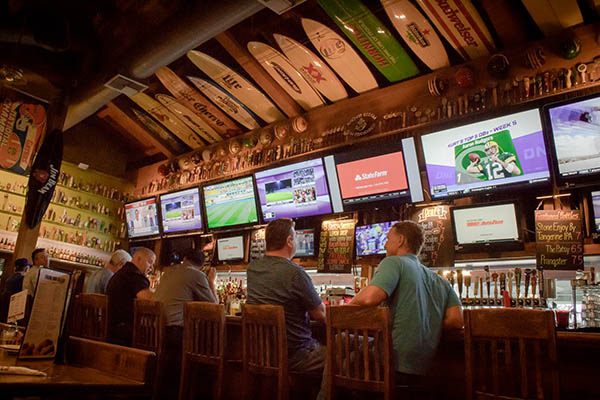 men sitting at bar watching sports