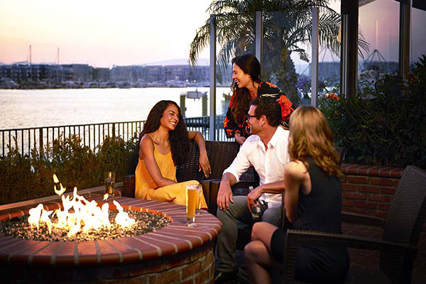 group of people sitting next to fire pit with cocktails