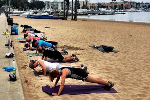 people in a plank pose during a yoga class on the beach