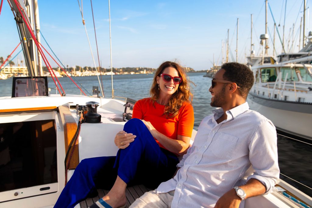 Couple sitting and smiling at each other on sailboat in Marina harbor