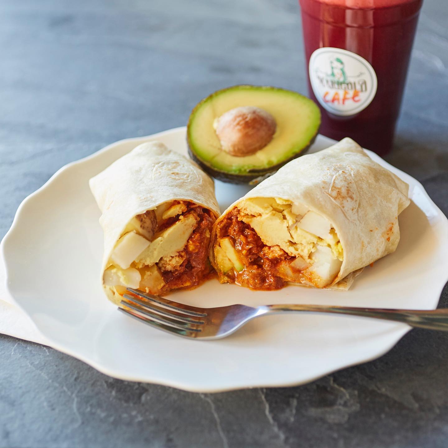 vegan breakfast burrito on a plate with half open avocado
