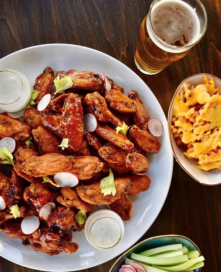 Bowl of chicken wings with a glass of beer and cheese fries