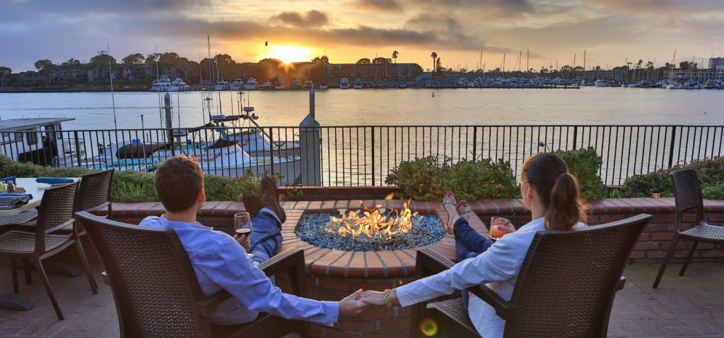 couple watching sunset at restaurant with fire pit while they eat in Marina del rey