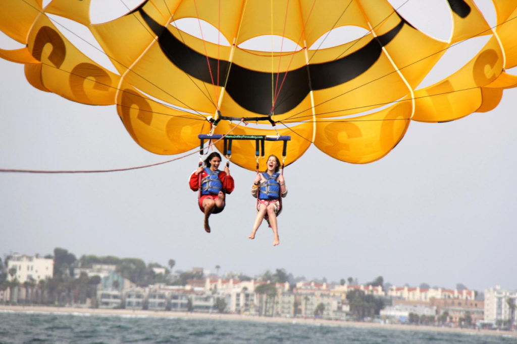two girls flying in the sky through parasailing