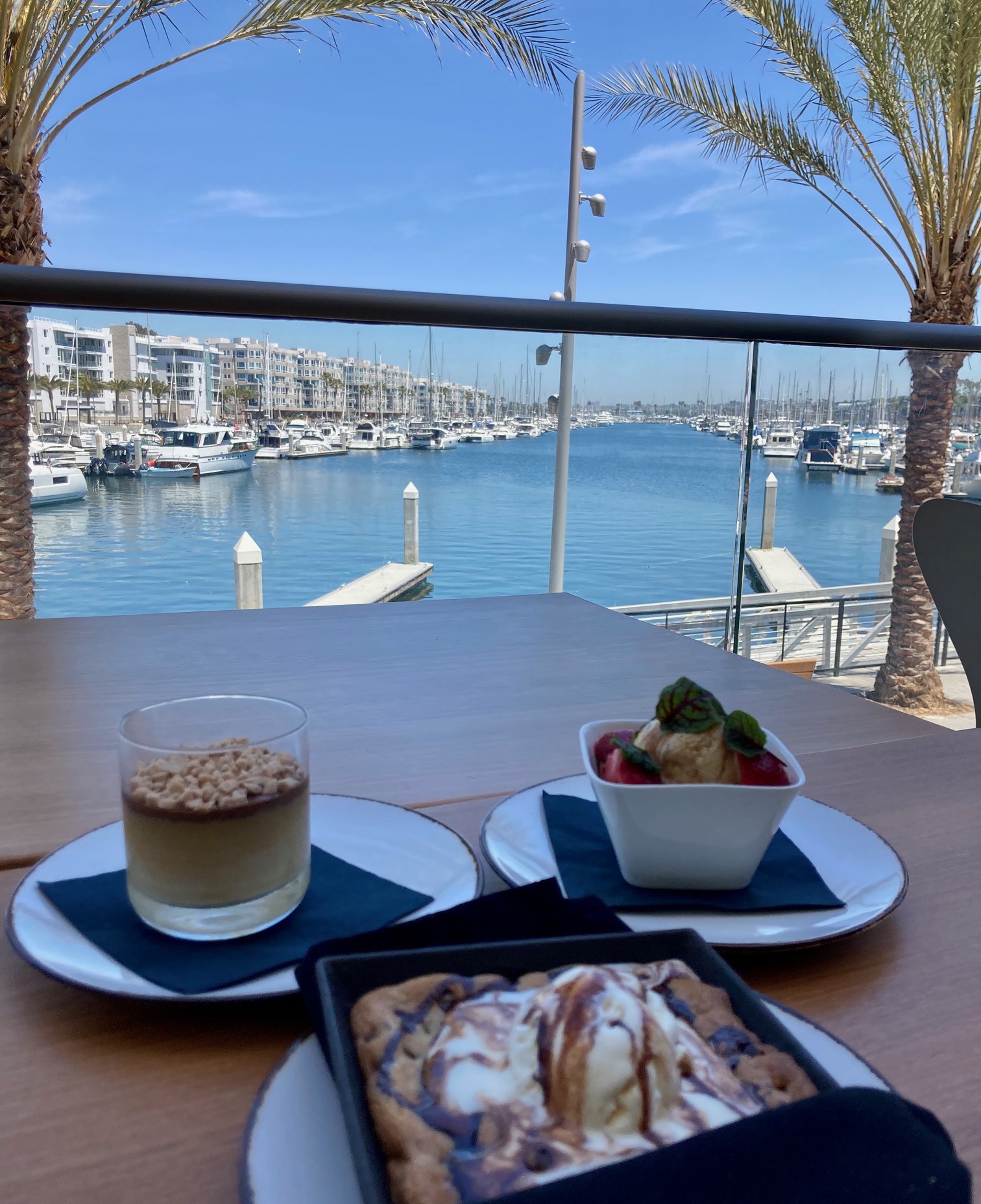 three desserts facing harbor with water at restaurant