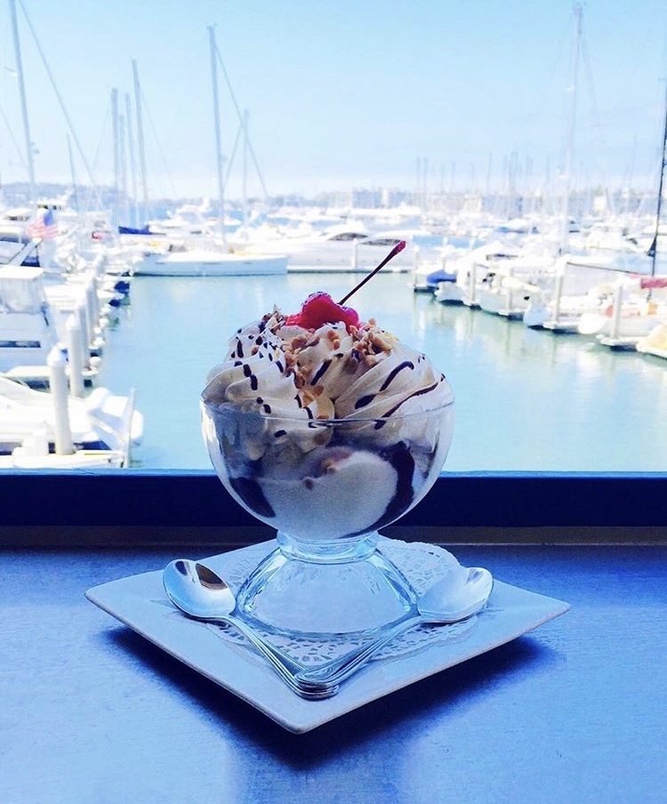 hot fudge brownie sundae on patio table facing harbor with boats