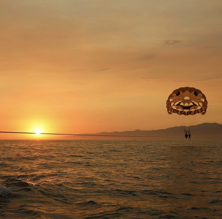 Parasailing over Pacific during sunset orange sky