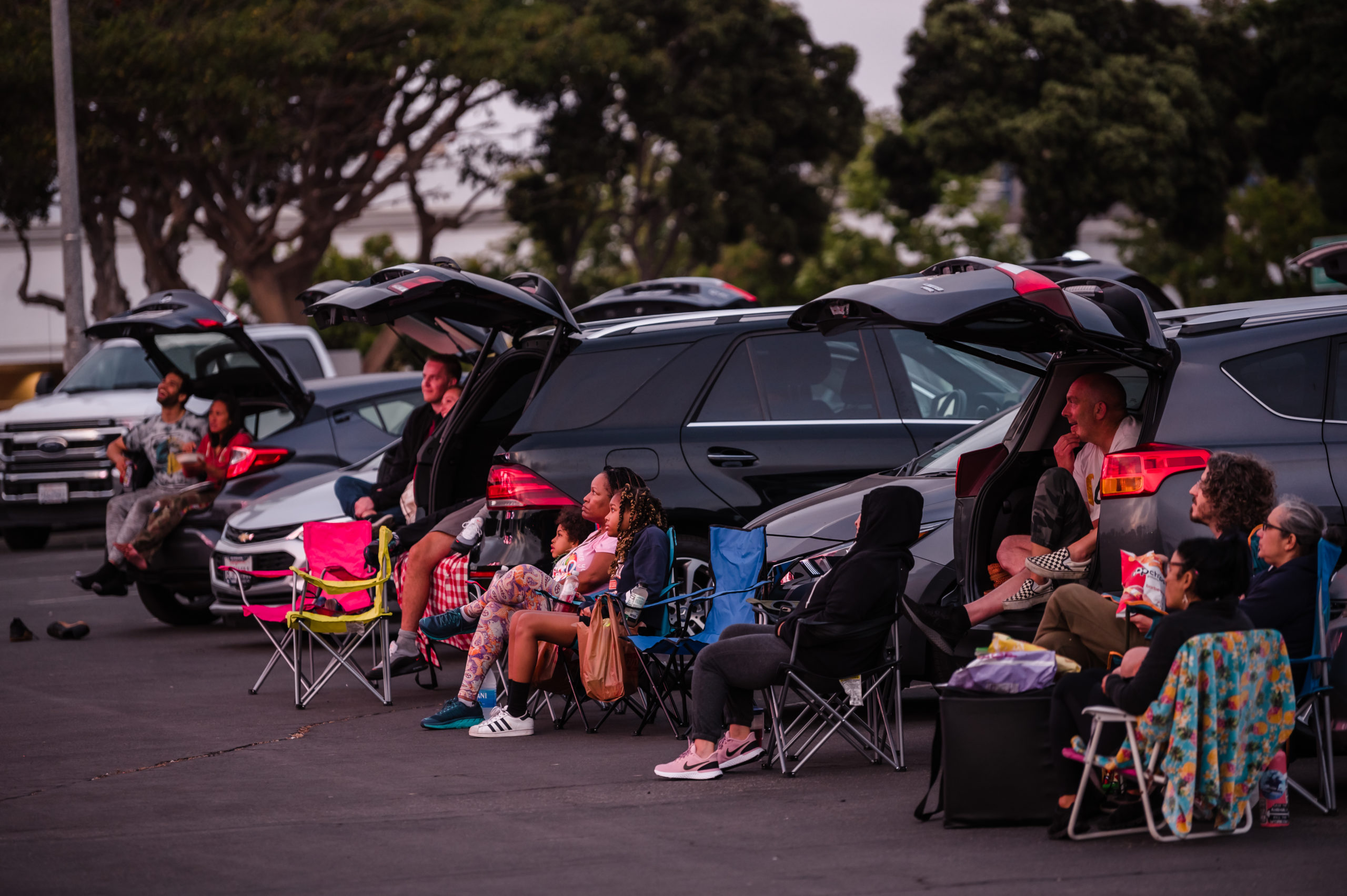 Group seated on lawn chairs watching movie outside at Marina Drive-In
