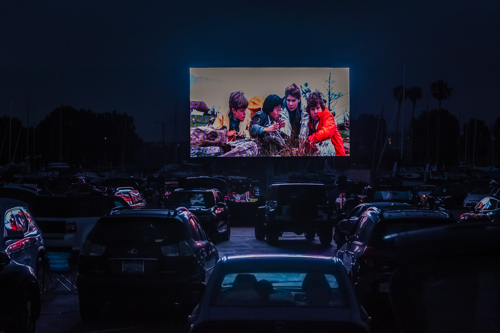 Cars parked in front of large screen for drive-in movie
