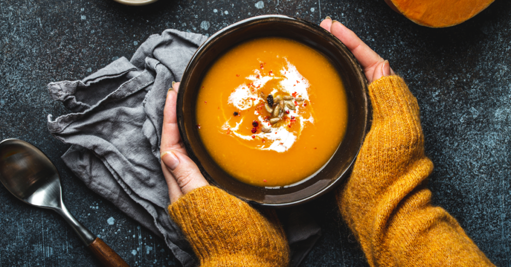 Hands around bowl of pumpkin soup