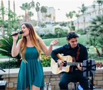 singer and guitarist performing outside with palm trees in background