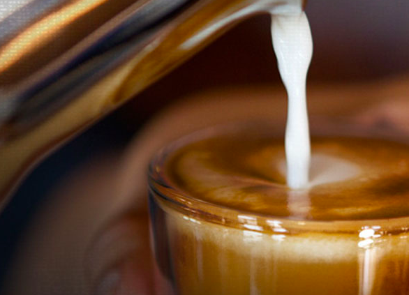 Milk being poured into specialty coffee latte drink