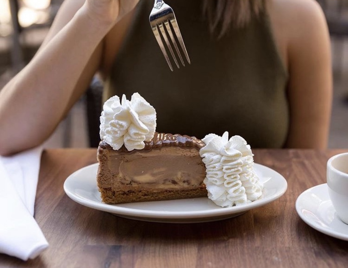 Slice of chocolate cheesecake on a plate with whip cream