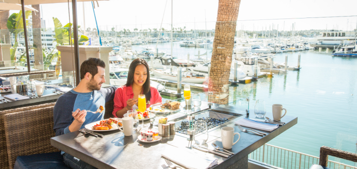 two people enjoying brunch at patio outside of MDR restaurant facing the harbor and boats