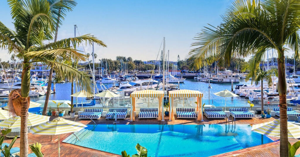 Pool cabanas with palm trees next to marina with boats