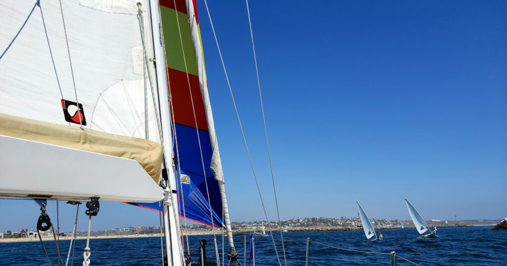 View from a sailboat looking into Marina del Rey channel with other sailboats in the sea