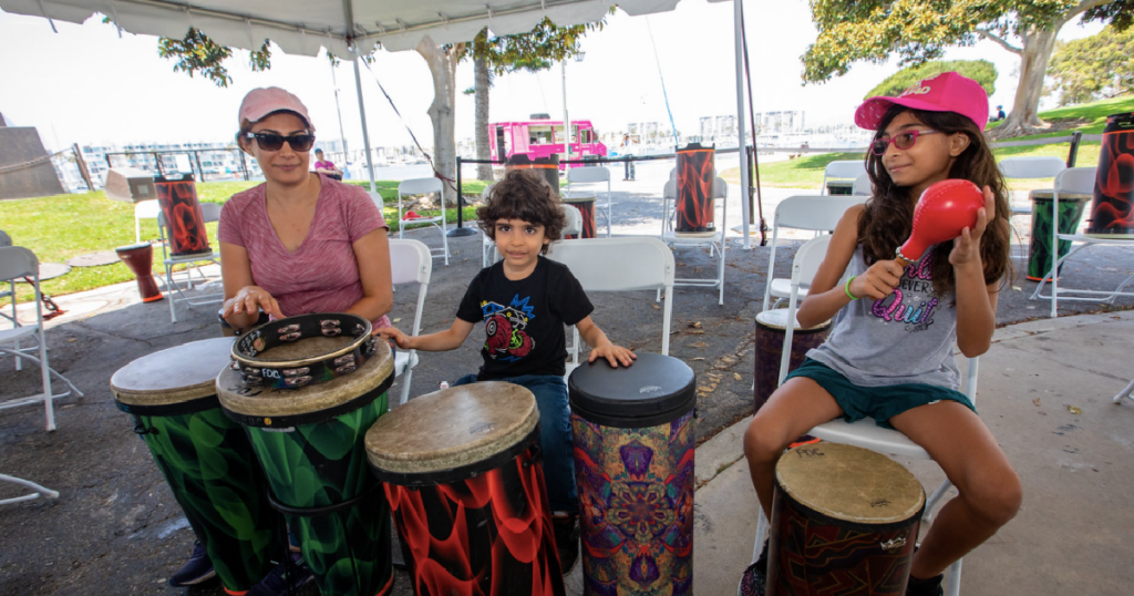 Mom and two children banging on drums in a park