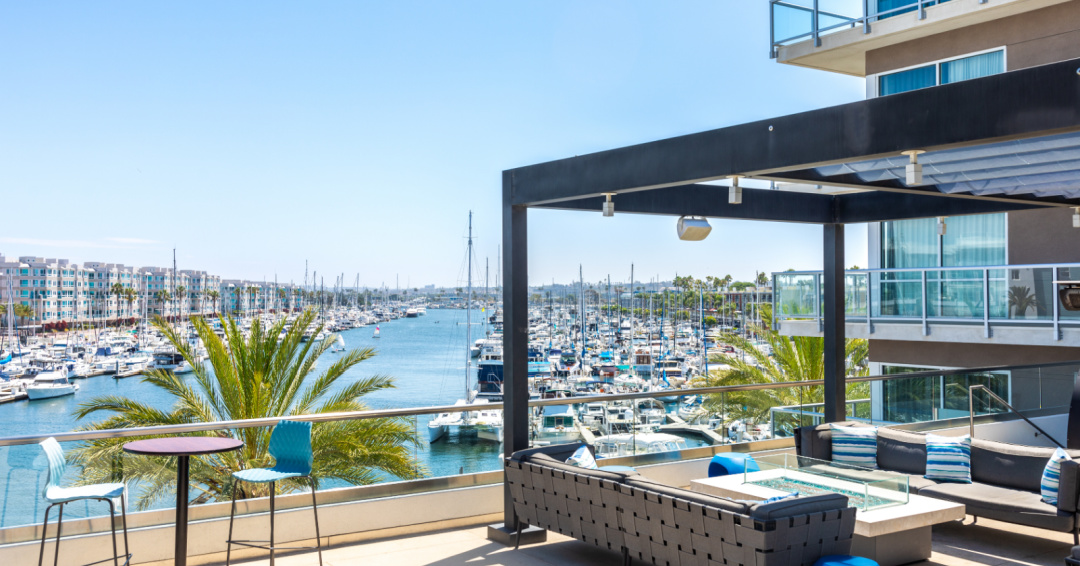 Rooftop deck with lounge chairs overlooking boats and harbor