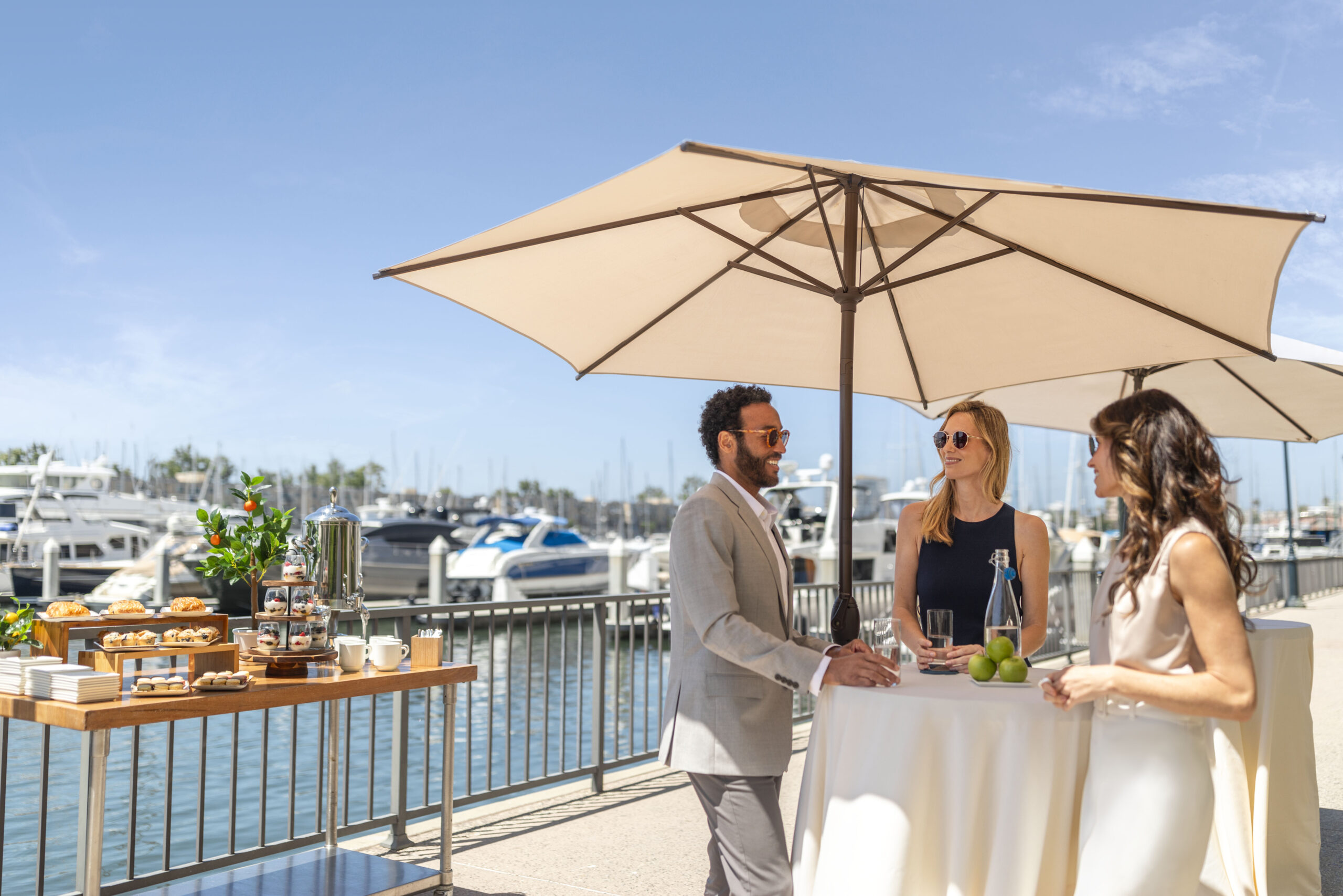 Group business meeting break under umbrella with snacks next to the harbor and boats