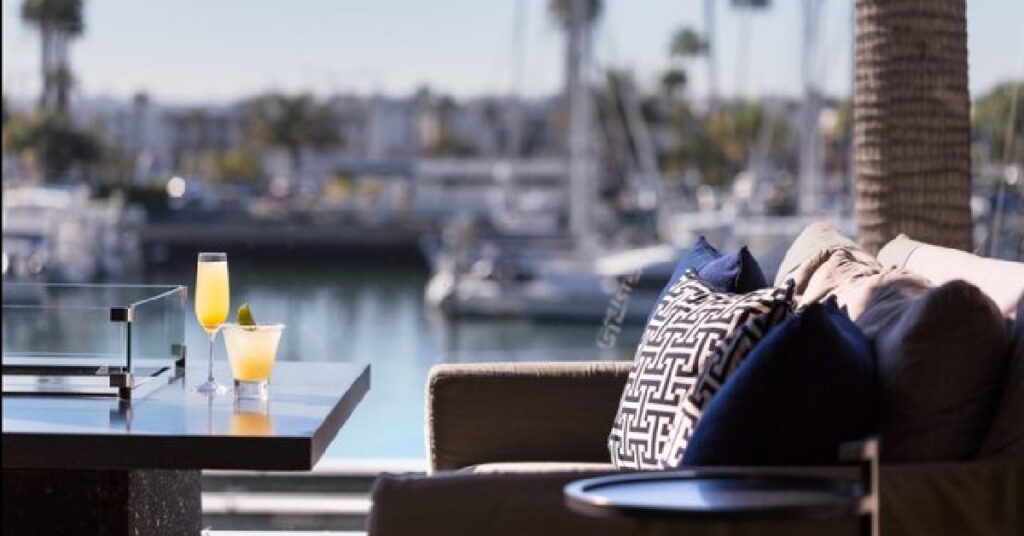 Drinks on outdoor table and cozy chairs overlooking water and harbor with boats