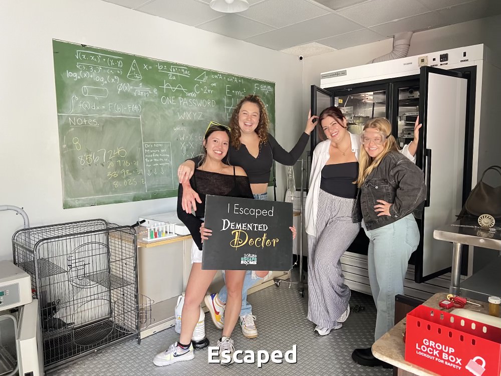 Group in escape room holding sign that says "We escaped"